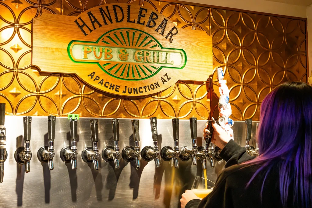 Purple-haired bartender pours beer at Handlebar Pub, Apache Junction AZ.