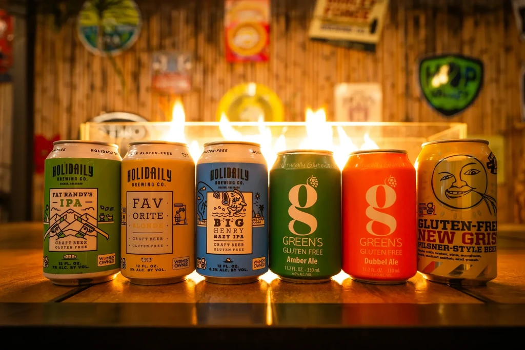 Six distinct gluten-free beer cans lined on a reflective bar.