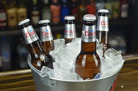 Five Coors Light beers in an ice bucket at a bar.
