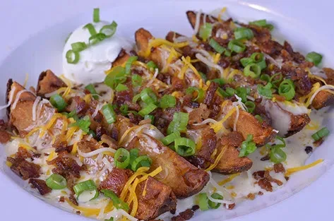 Loaded potato wedges with melted cheese, bacon, green onions, and sour cream.