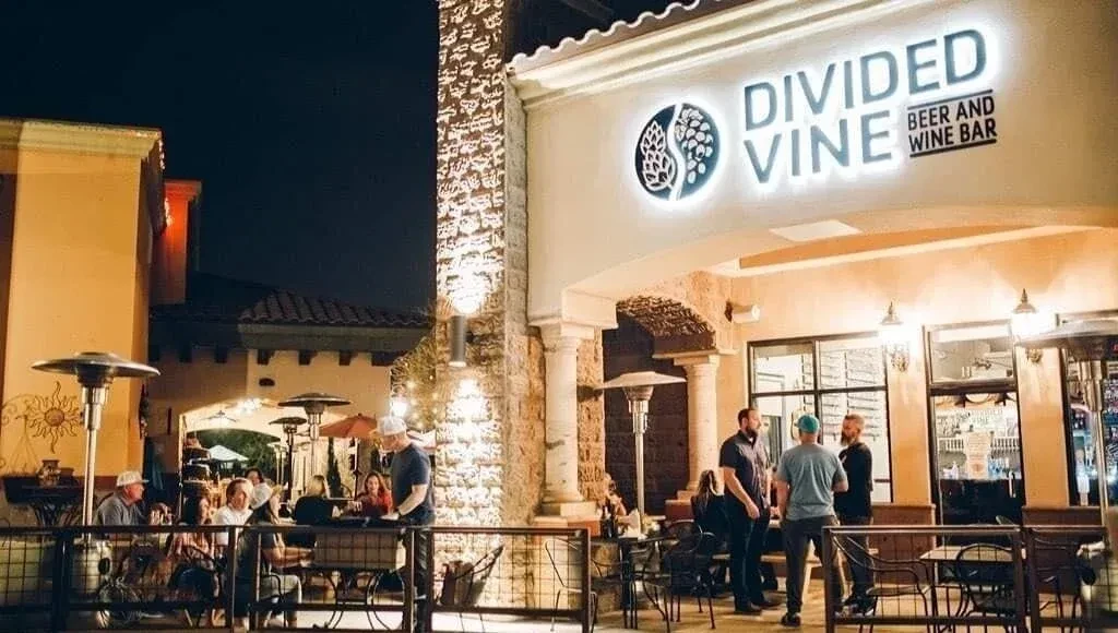 Divided Vine Beer and Wine Bar exterior at night, people on patio.