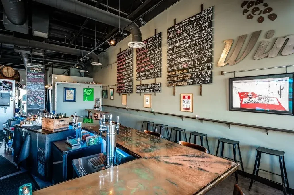 Empty industrial bar with a unique copper counter, beer taps, and menus.