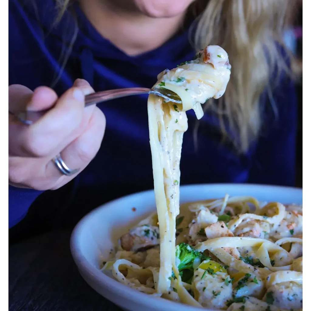 Fork lifts creamy fettuccine with chicken, broccoli, and herbs.