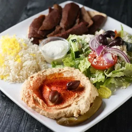A Middle Eastern meal with meat, rice, hummus, and salad.