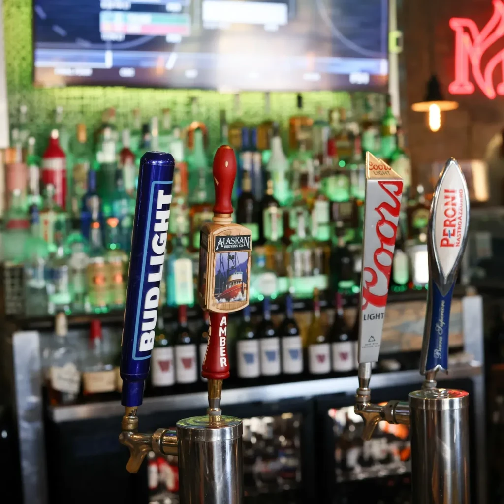 Four beer tap handles: Bud Light, Alaskan Amber, Coors Light, Peroni.