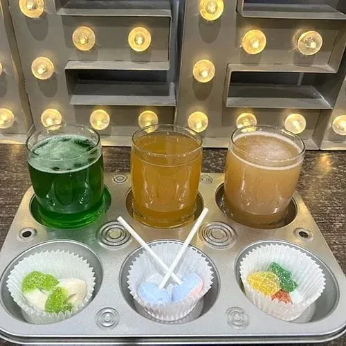 Flight of three drinks and three candies in a muffin tin.