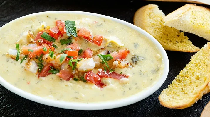 Creamy seafood dish with tomatoes, herbs, and toasted bread.