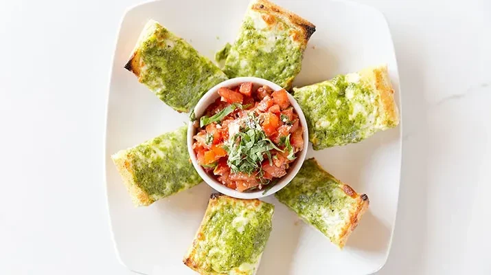 Appetizer: pesto bread, melted cheese, and tomato bruschetta.