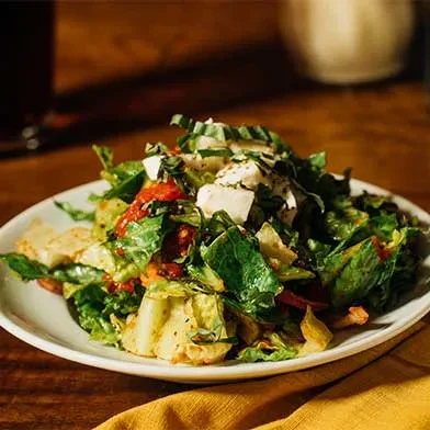 Vibrant salad with lettuce, white cheese, tomatoes, and basil on wood.