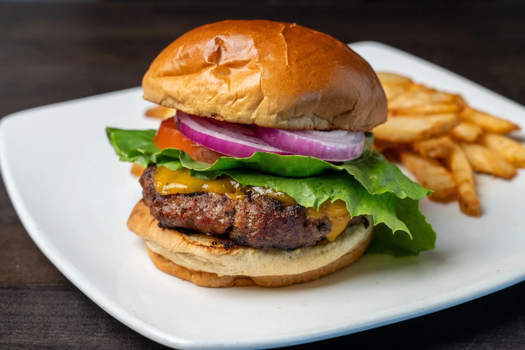 Cheeseburger with melted cheddar, lettuce, tomato, onion, and golden fries.