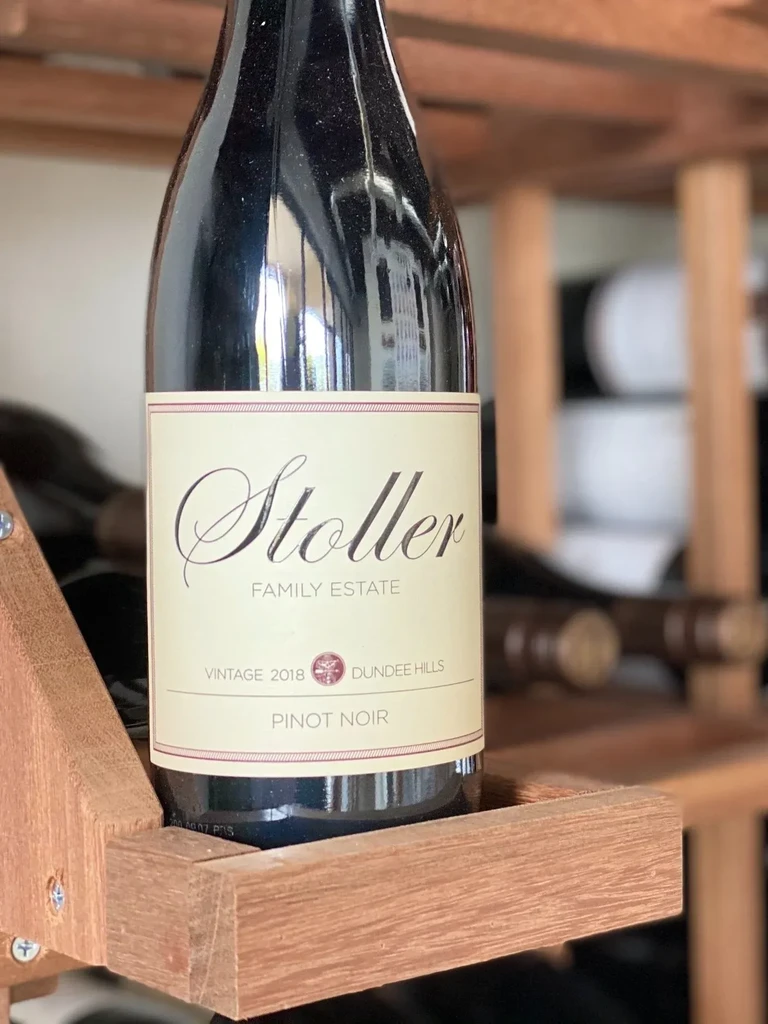 Stoller Family Estate 2018 Pinot Noir bottle in a wooden rack.