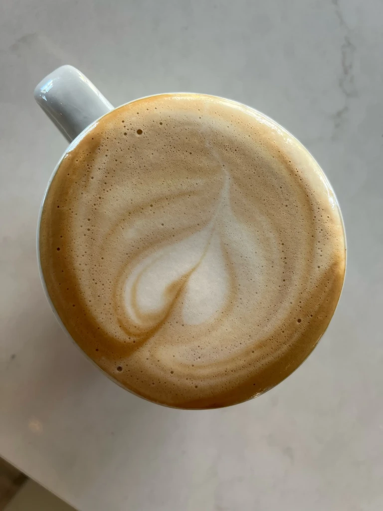 White ceramic mug with creamy latte and distinct white heart art.