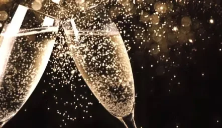 Two champagne flutes clinking in a toast with golden bubbles.