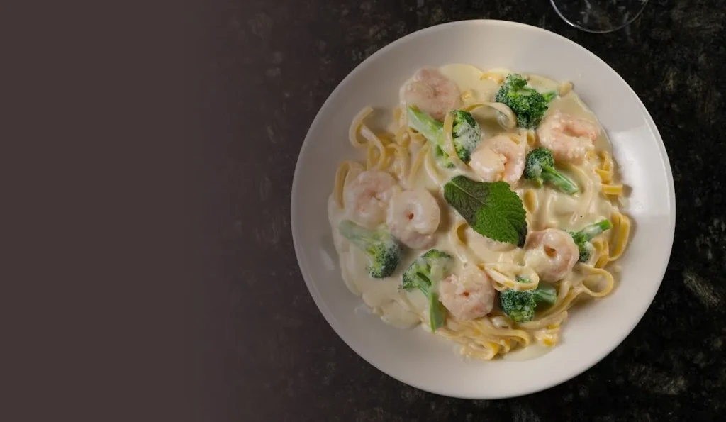 A top-down view of creamy shrimp and broccoli fettuccine with mint.