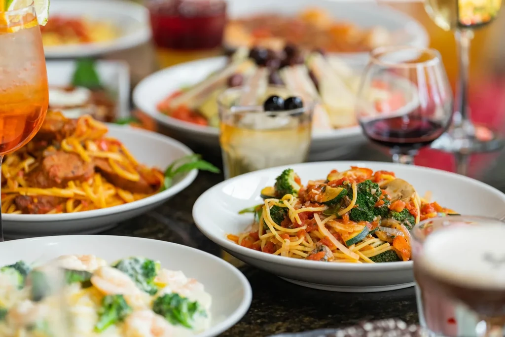Dining table with assorted pasta dishes and beverages.