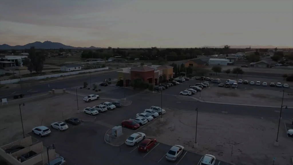 Aerial view: Busy Southwestern restaurant at dusk, desert landscape, mountains.