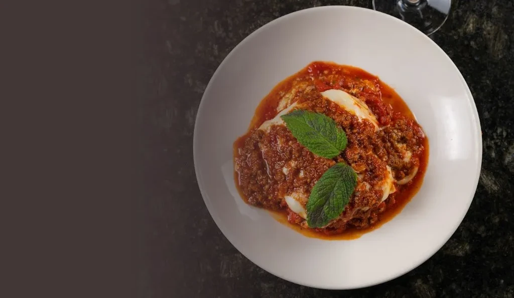Baked pasta with rich meat sauce, melted cheese, and fresh mint.