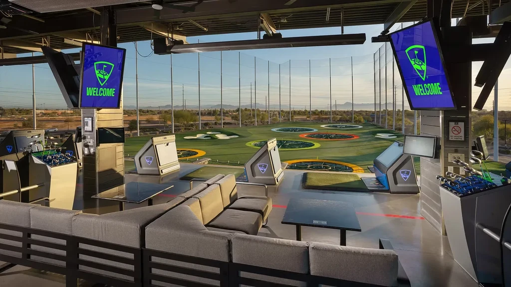 Empty Topgolf facility: open-air bays, lounge, and driving range.