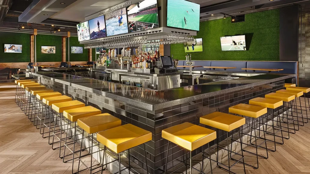 The Larking Stick Resort Bar interior with yellow stools and many TVs.