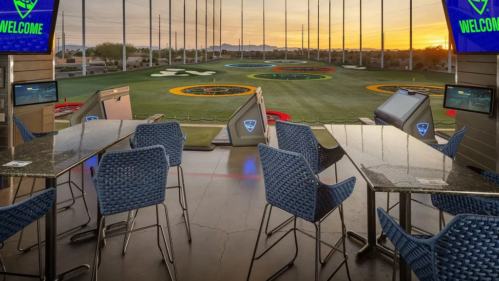 Topgolf driving range bay at sunset with colorful targets.