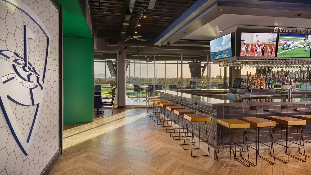 Topgolf bar and restaurant with liquor, TVs, and golf range view.