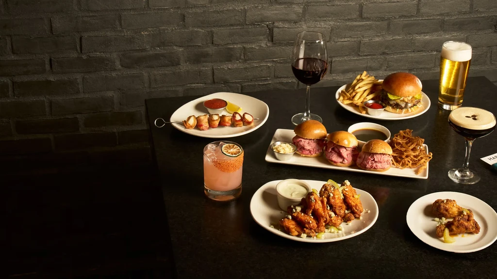 Artful display of burgers, wings, fries, and assorted alcoholic drinks.