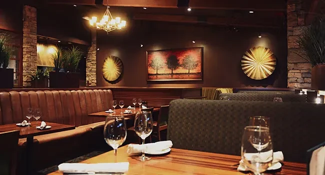 Upscale, empty restaurant interior with dark wood tables and warm lighting.