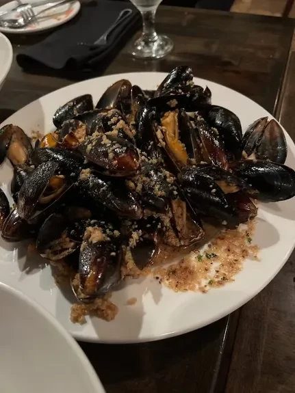 Plate of steamed mussels with breadcrumbs and light broth.