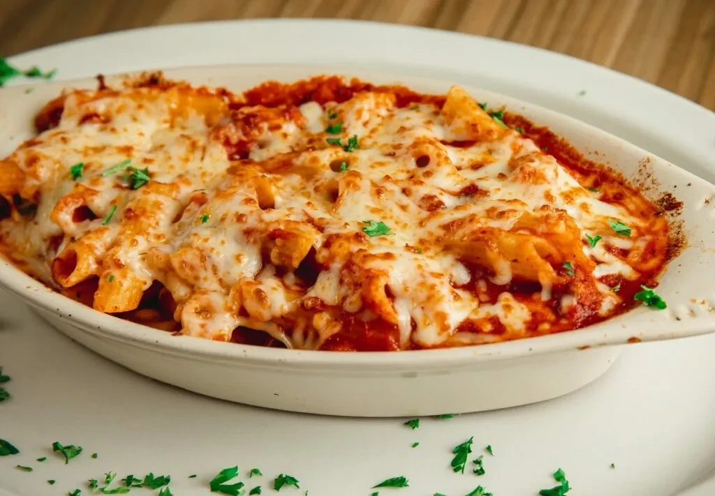 Baked pasta with red sauce, melted mozzarella, and green herbs.