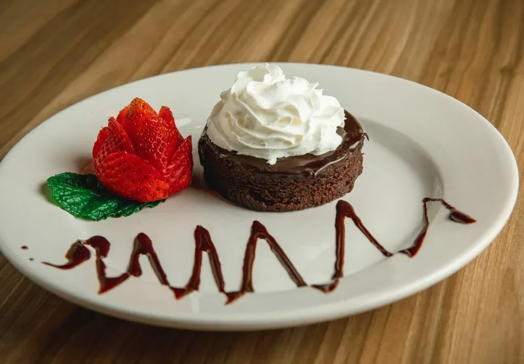 Dark chocolate cake with whipped cream, strawberry rose, and mint.