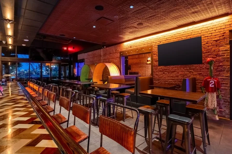 Modern restaurant interior with industrial bar, exposed brick wall, and green alien.