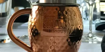 Hammered copper Moscow Mule mug on a white tablecloth.