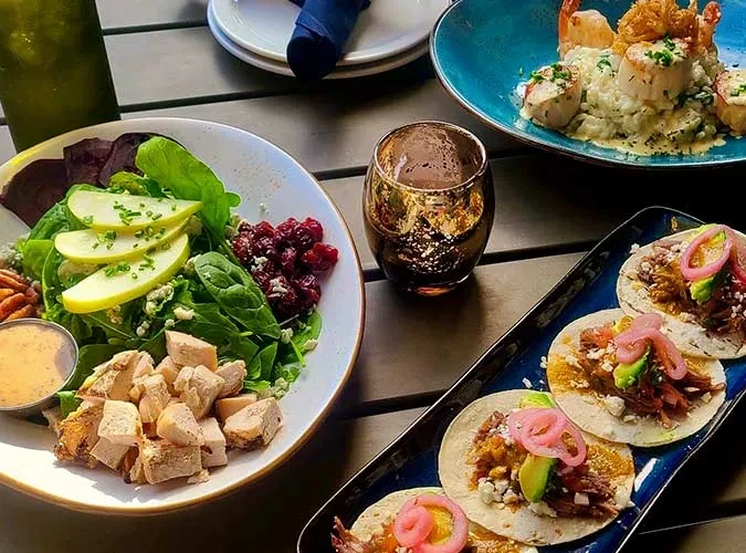 Overhead view of a restaurant table with salad, seafood, and tacos.