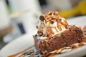 Brownie topped with ice cream, caramel, chocolate syrup, nuts, and chips.