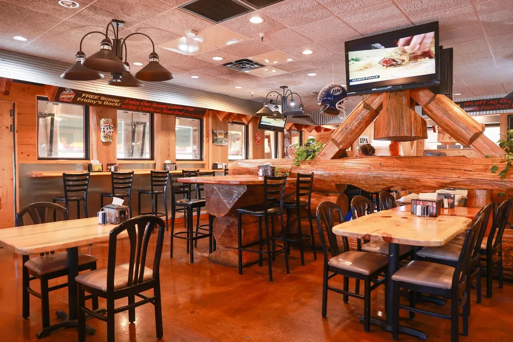 Rustic, log-cabin style restaurant interior with wood furniture and a central log beam.
