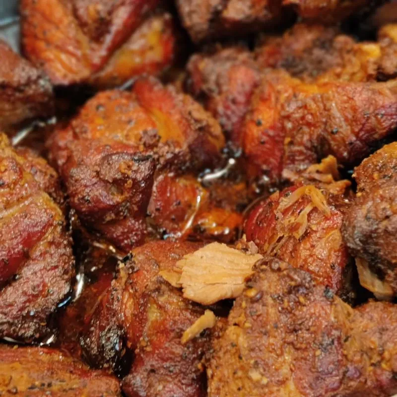 Close-up of tender, dark braised meat glistening with savory sauce.