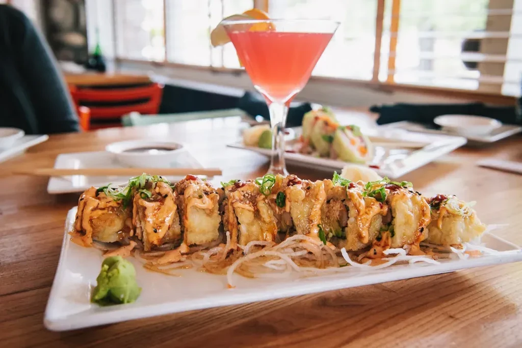 Tempura sushi rolls with creamy orange sauce, wasabi, and pink cocktail.