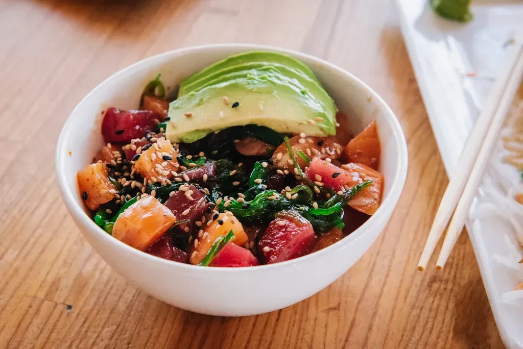 Vibrant poke bowl with tuna, salmon, avocado, seaweed, sesame.