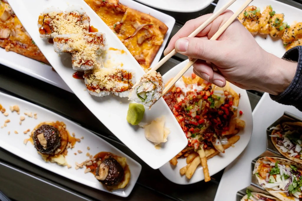 Overhead view of hand picking sushi from diverse dishes.