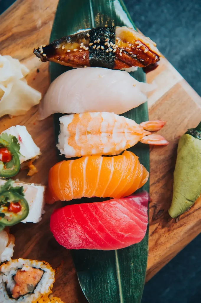 Colorful sushi and sashimi variety on a rustic wooden board.