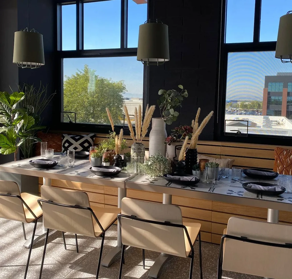 Empty modern dining area with a long, decoratively set communal table.
