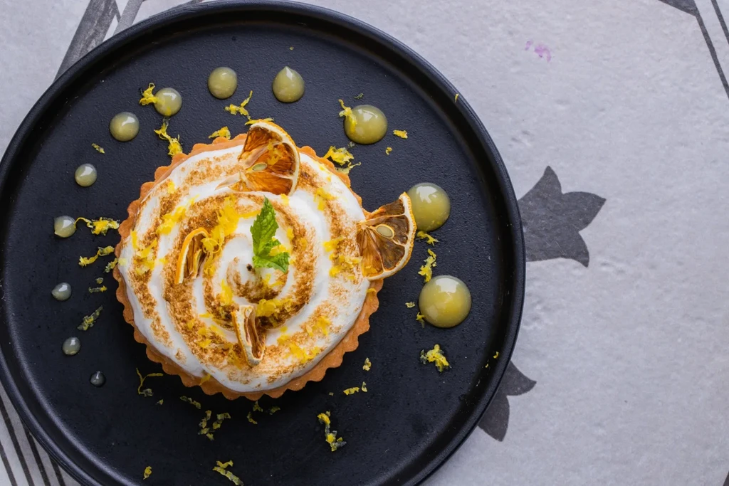 Lemon meringue tart with toasted meringue, zest, mint, and green sauce.