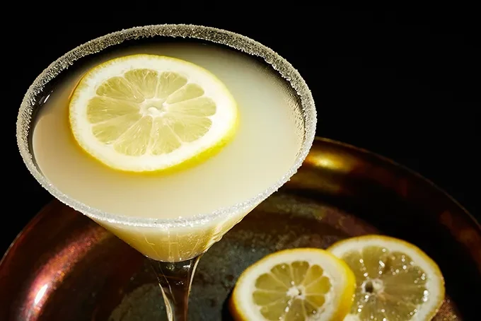 Bright yellow cocktail in martini glass, sugared rim, lemon garnish.