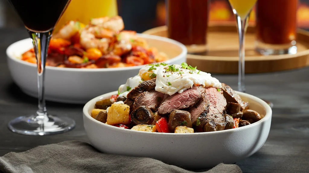 Close-up of steak and potato dish with creamy topping and drinks.
