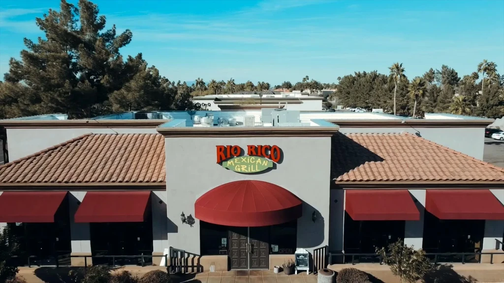 Rio Rico Mexican Grill, red awnings, tiled roof, palm trees, sunny.