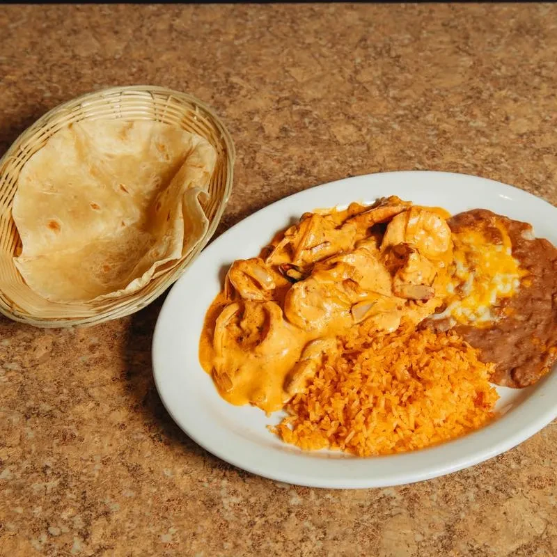 A plate of shrimp, Spanish rice, refried beans, and tortillas.