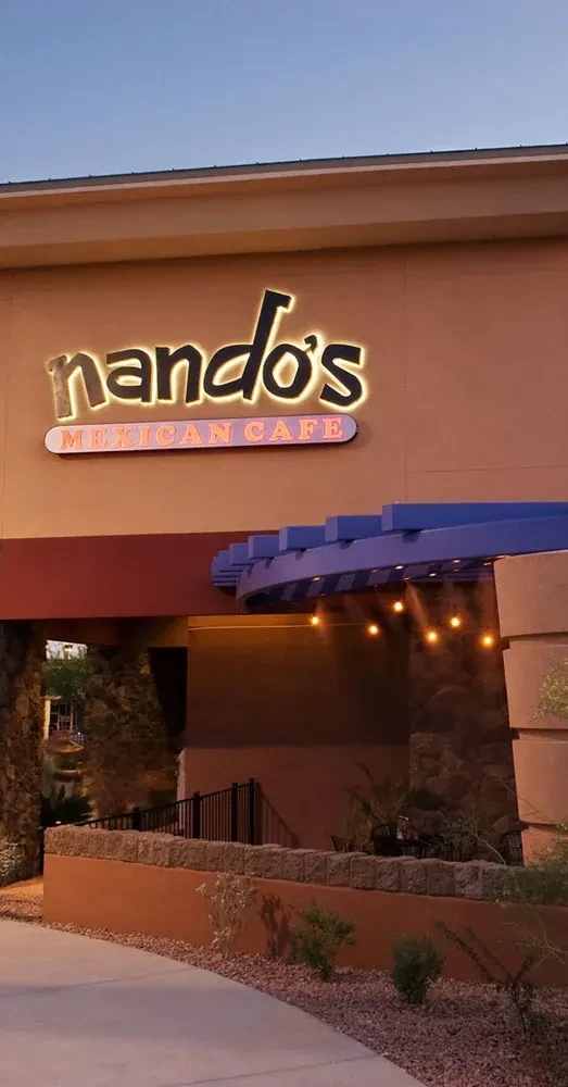 Nando's Mexican Cafe exterior at dusk, bright neon, blue awning.