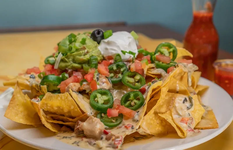 Loaded nachos with guacamole, sour cream, jalapeños, and queso sauce.