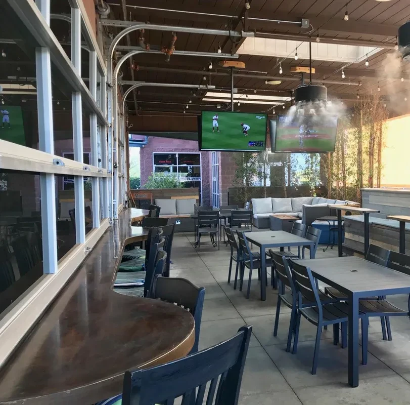 Casual open-air patio with a bar and TVs showing baseball.