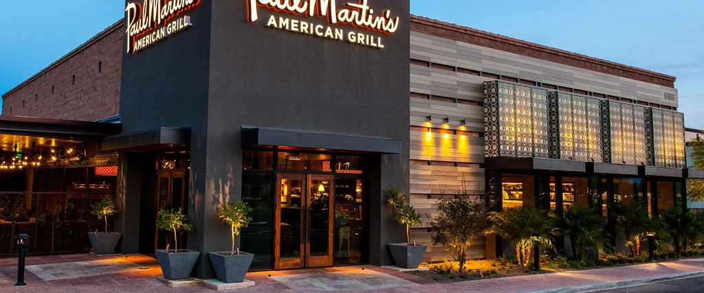 Modern Paul Martin's American Grill restaurant exterior glowing at dusk.